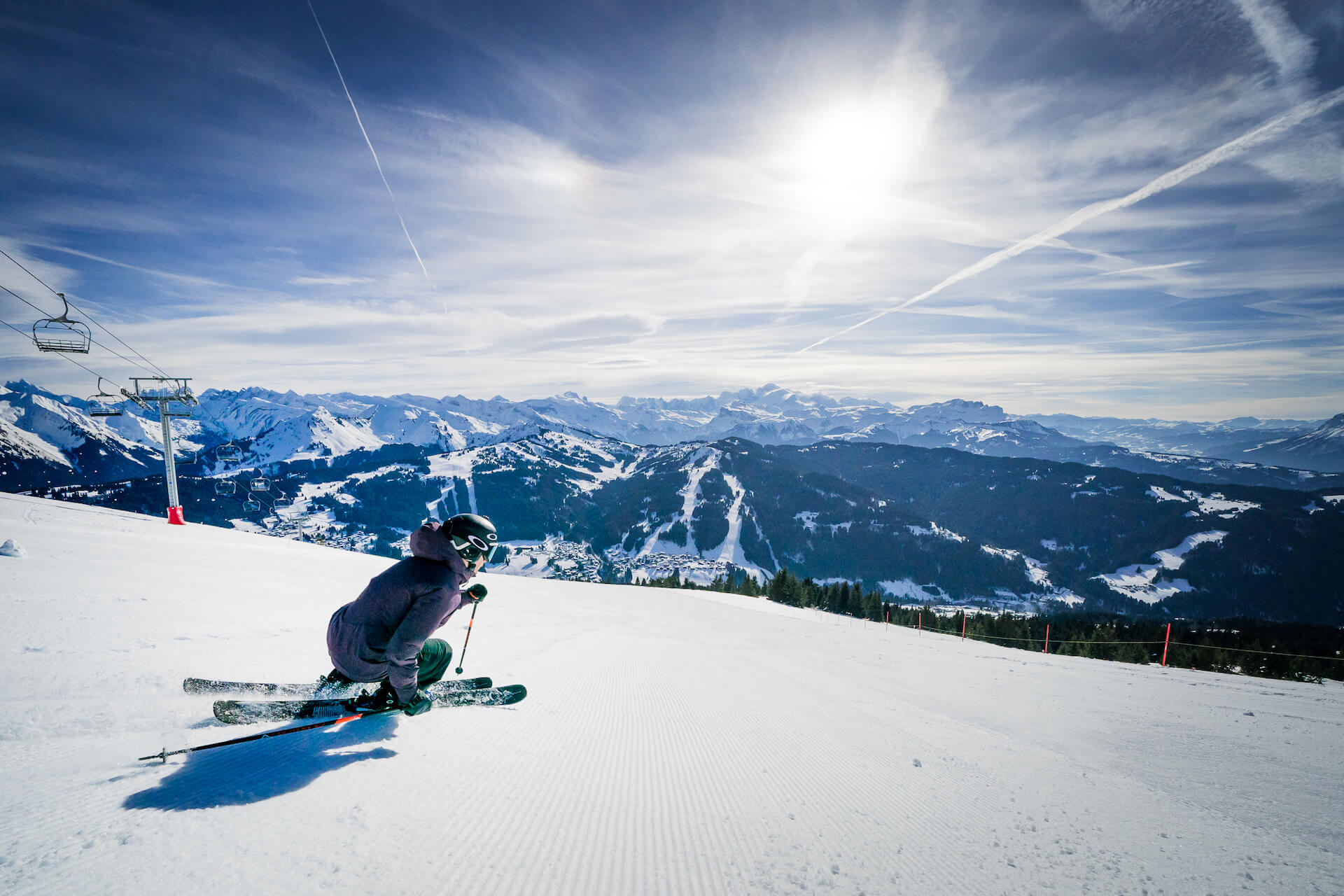 Skieur descendant une piste avec montagne et télésiège en fond
