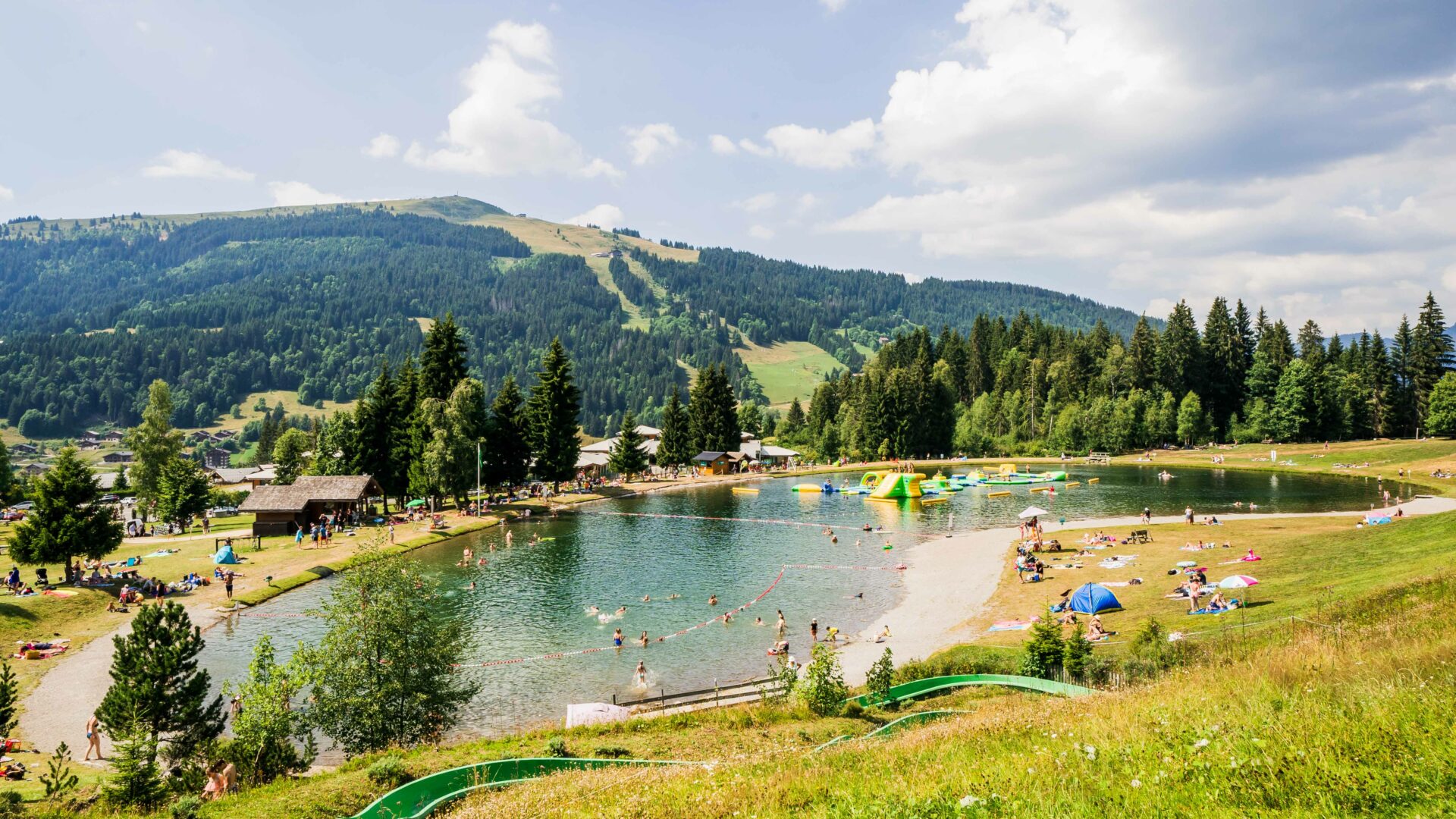 Mountain lake in summer with inflatable game and slide