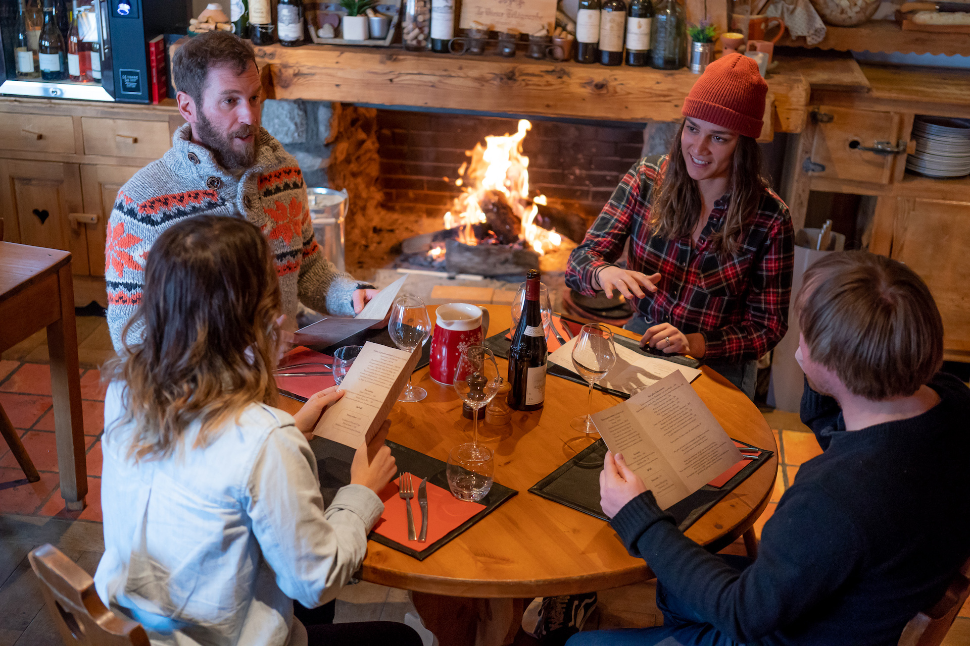 Amis choisissant leurs menus au restaurant avec cheminée en fond