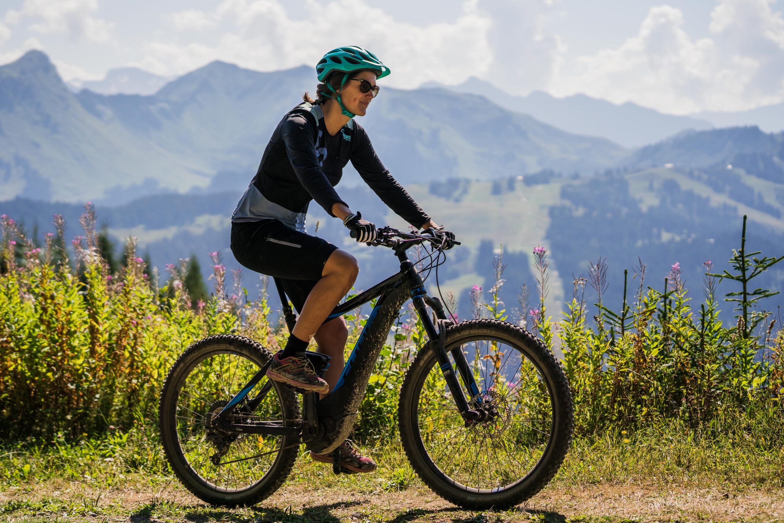 Femme faisant du VTT en été avec montagnes en fond