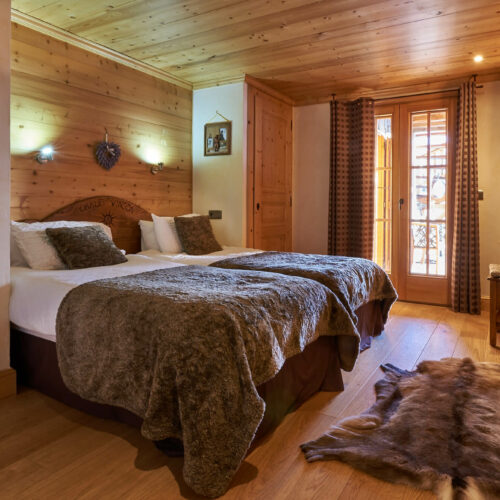 Chambre d'hôtel avec deux lits simples, tout en bois et peau de bête