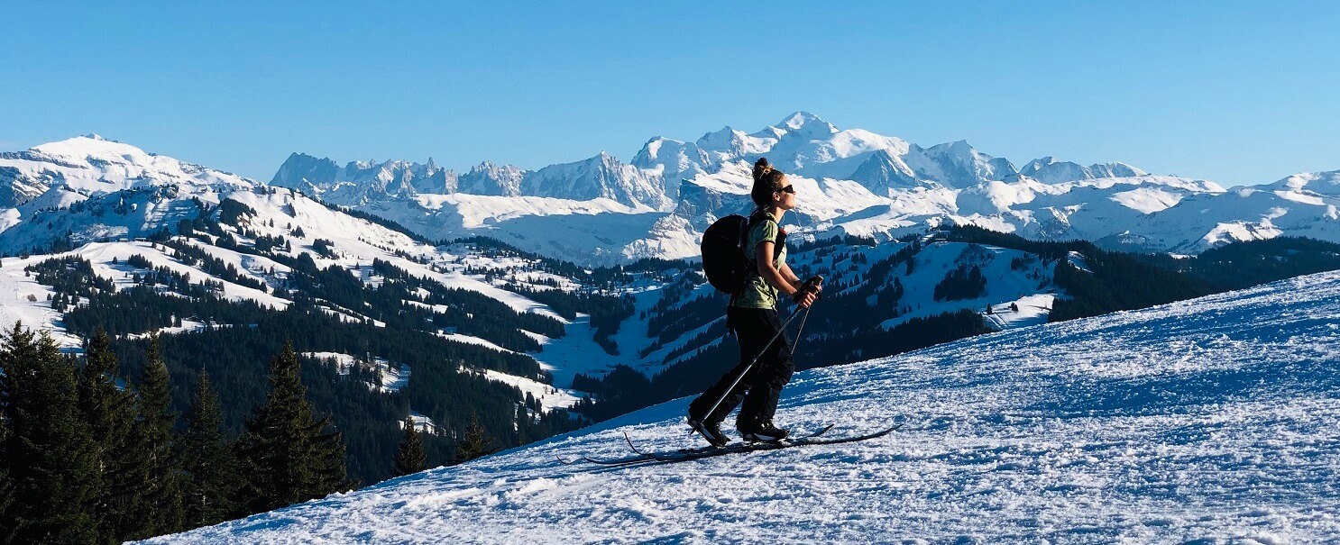 Femme faisant du ski de randonnée en hiver avec paysage montagnes derrière