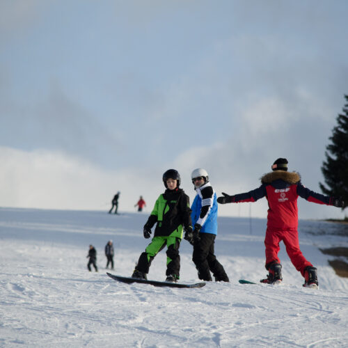 Vacanciers prenant un cours de snowboard avec un moniteur