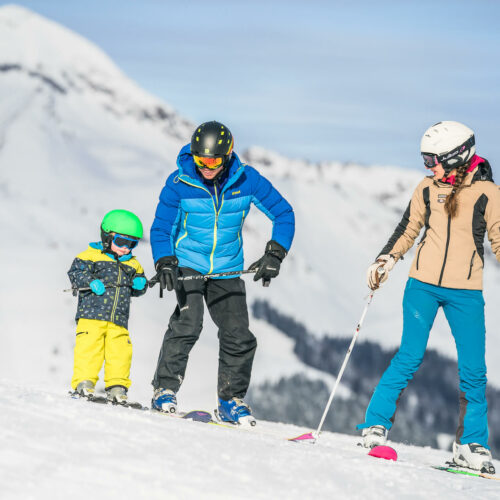 Famille en ski avec parents qui apprennent à leur enfant à skier