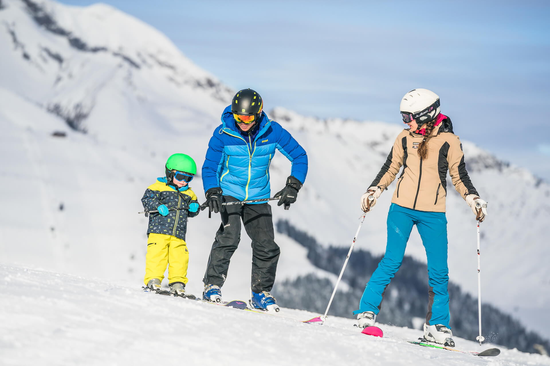 Famille en ski avec parents qui apprennent à leur enfant à skier