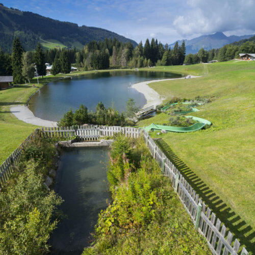 Vue d'ensemble d'un lac de montagne en été avec pelouses, toboggan et réserve d'eau