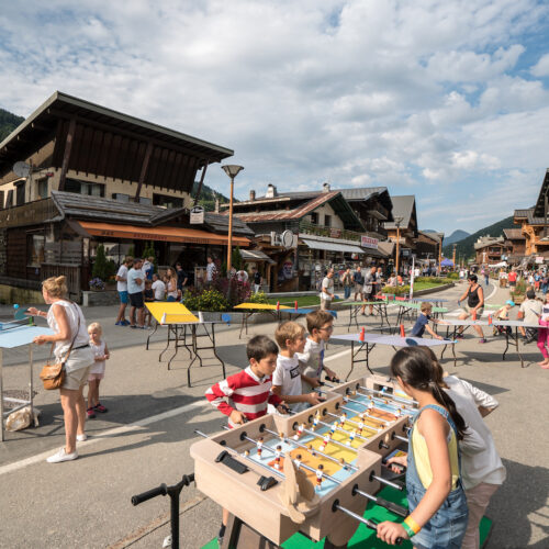 Vacanciers jouant à divers jeux : babyfoot, ping-pong...dans la rue du Centre des Gets