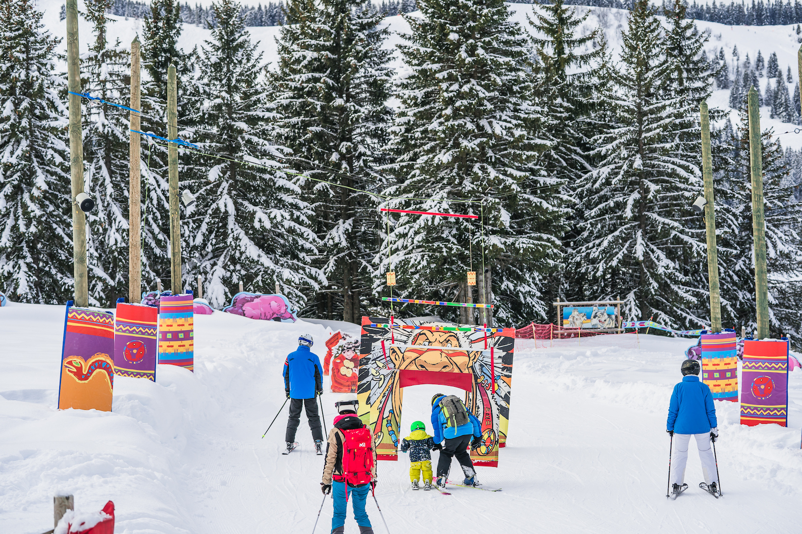 Famille en train de skier sur une piste aménagée pour les enfants avec décoration indiens