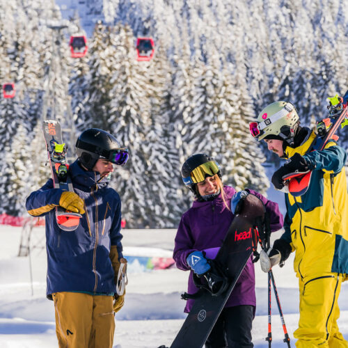 Skieurs et snowboardeuse discutant avec télécabine rouge derrière