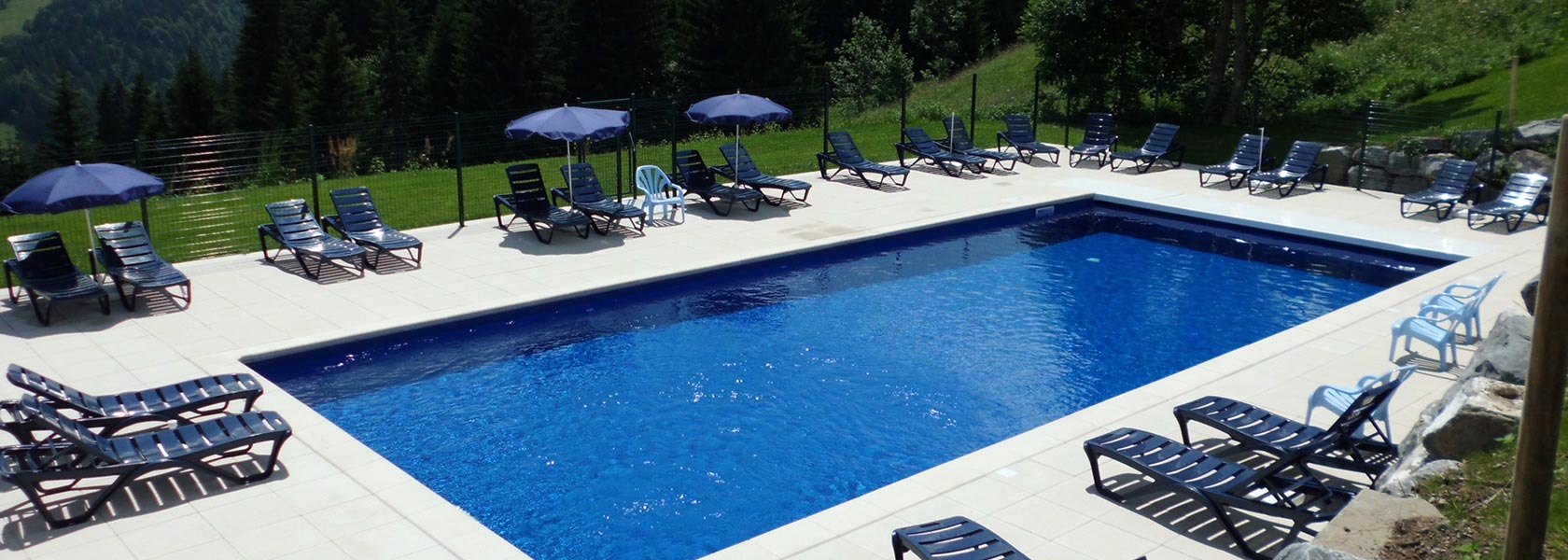 Piscine du camping des Gets avec parasols et transats.