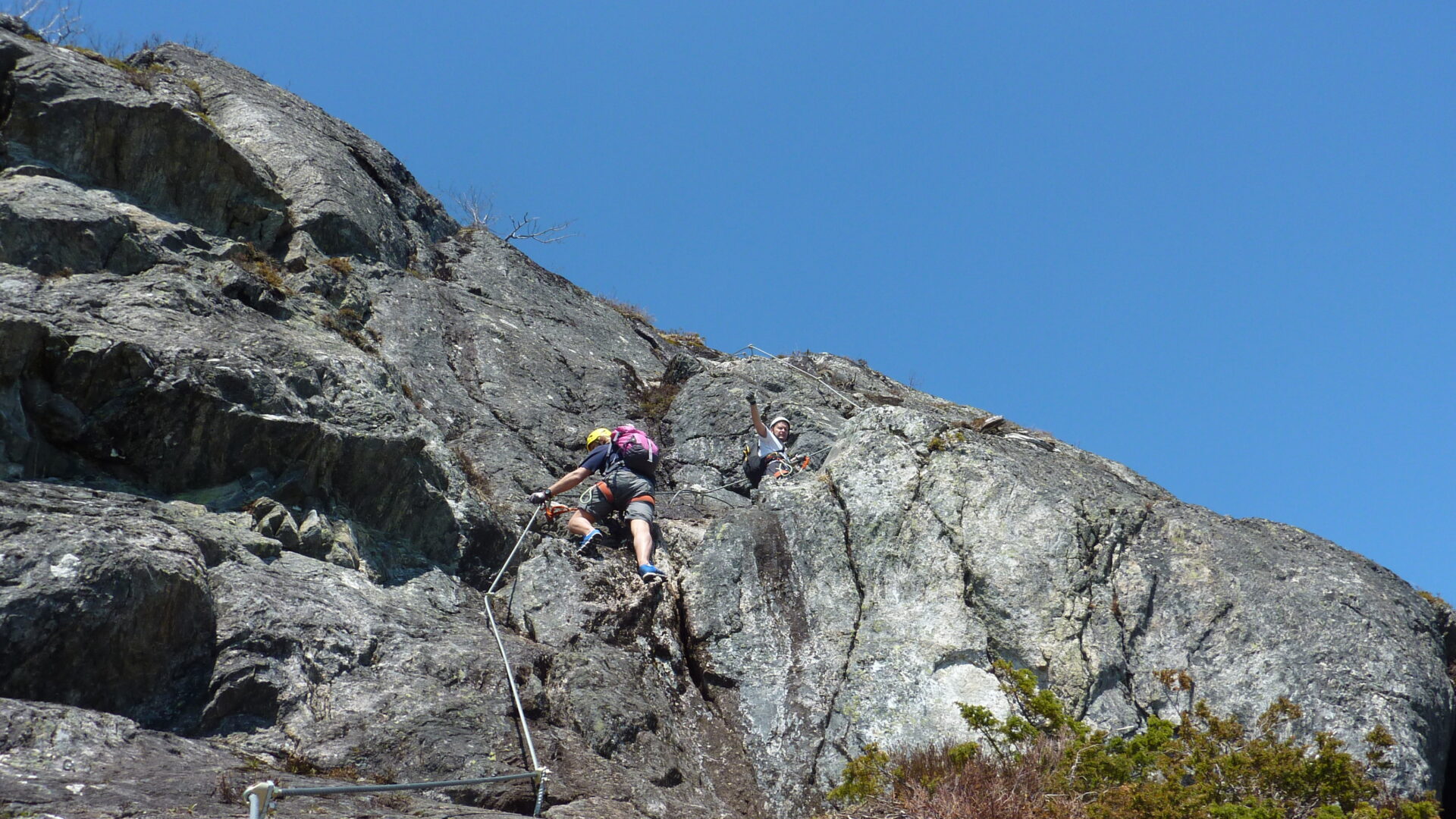 Personnes grimpant un rocher à l'aide d'une corde. Via ferrata