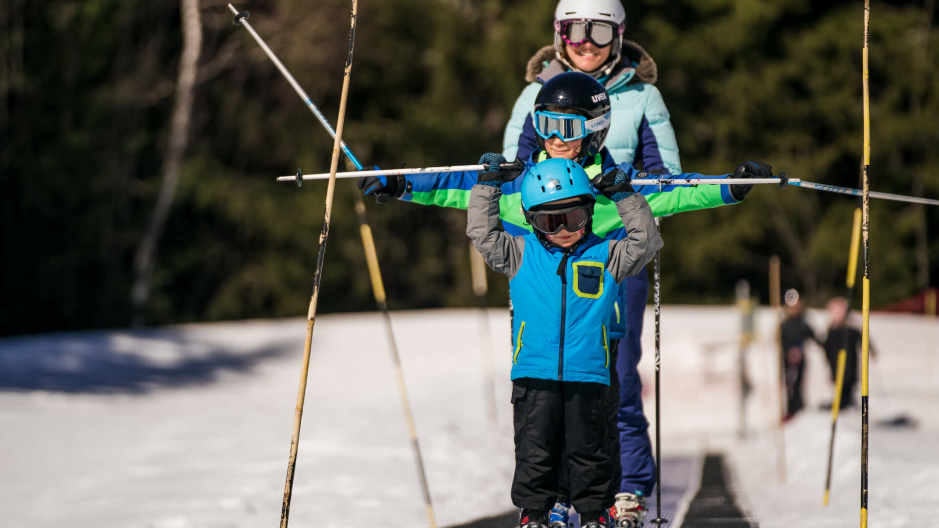 Enfants et leur maman sur tapis en ski