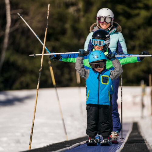 Enfants et leur maman sur tapis en ski