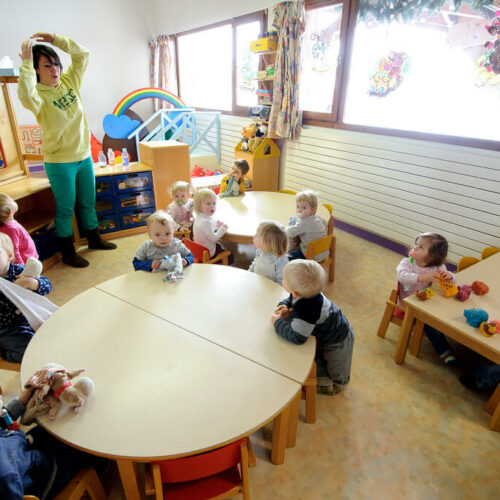 Enfants dans une garderie avec femme qui s'occupe d'eux