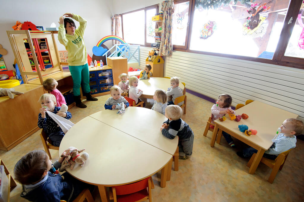 Enfants dans une garderie avec femme qui s'occupe d'eux